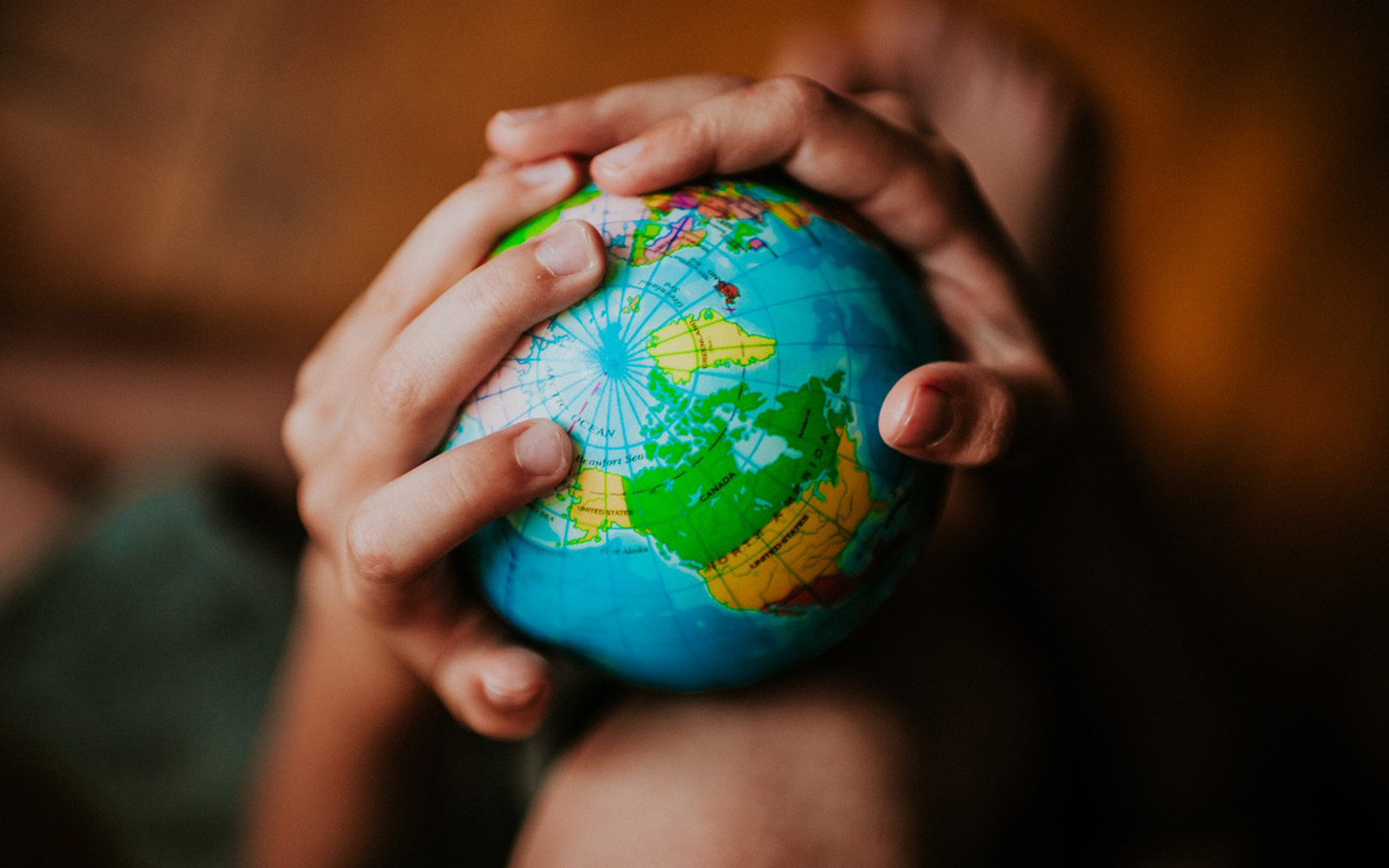 Close up of two hands around a globe.