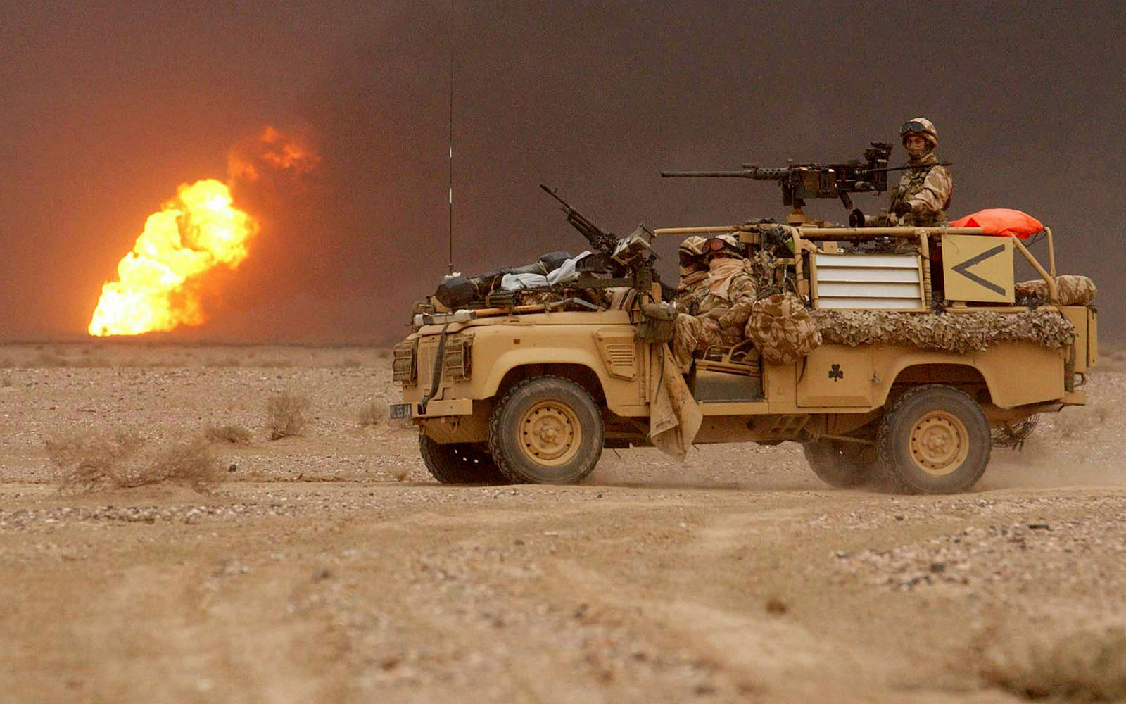 Image from Iraq during the Op Telic campaign. Image of a vehicle in a desert with a flame in the background.