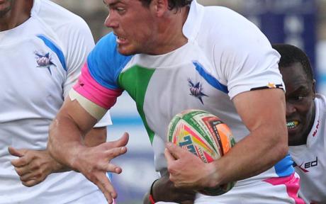 Close up of person holding a rugby ball mid-match.