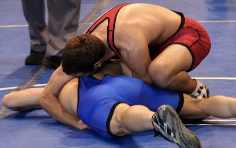 Two people wrestling each other on a mat.