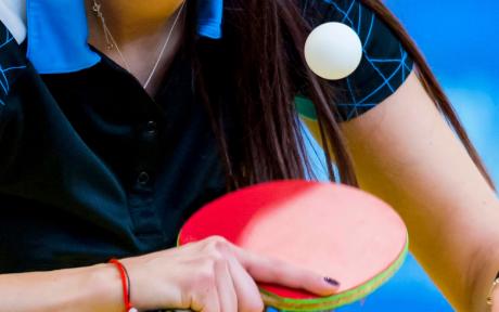 Close up of someone mid swing during a table tennis match.