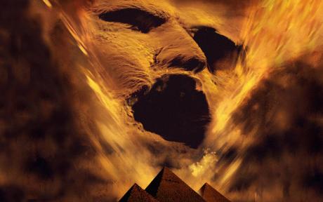 Movie still from the film the Mummy. Sandy image of a face overlooking pyraminds.