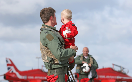 Father in RAF uniform holding a child. Red Arrow in background.