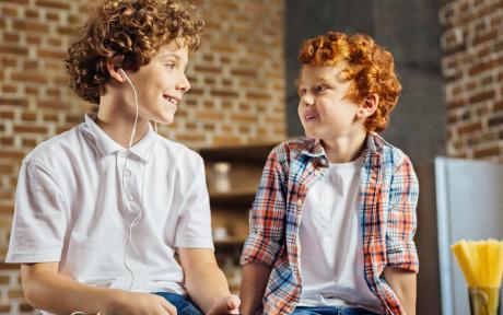 Two children, sat opposite each, other smiling.
