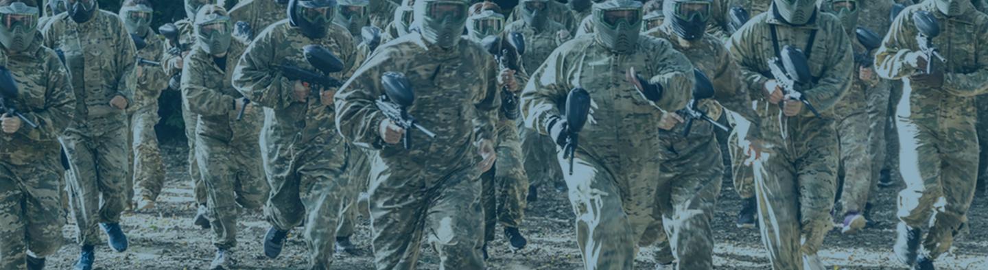 Gathering of folk in camouflage gear with paintball guns.